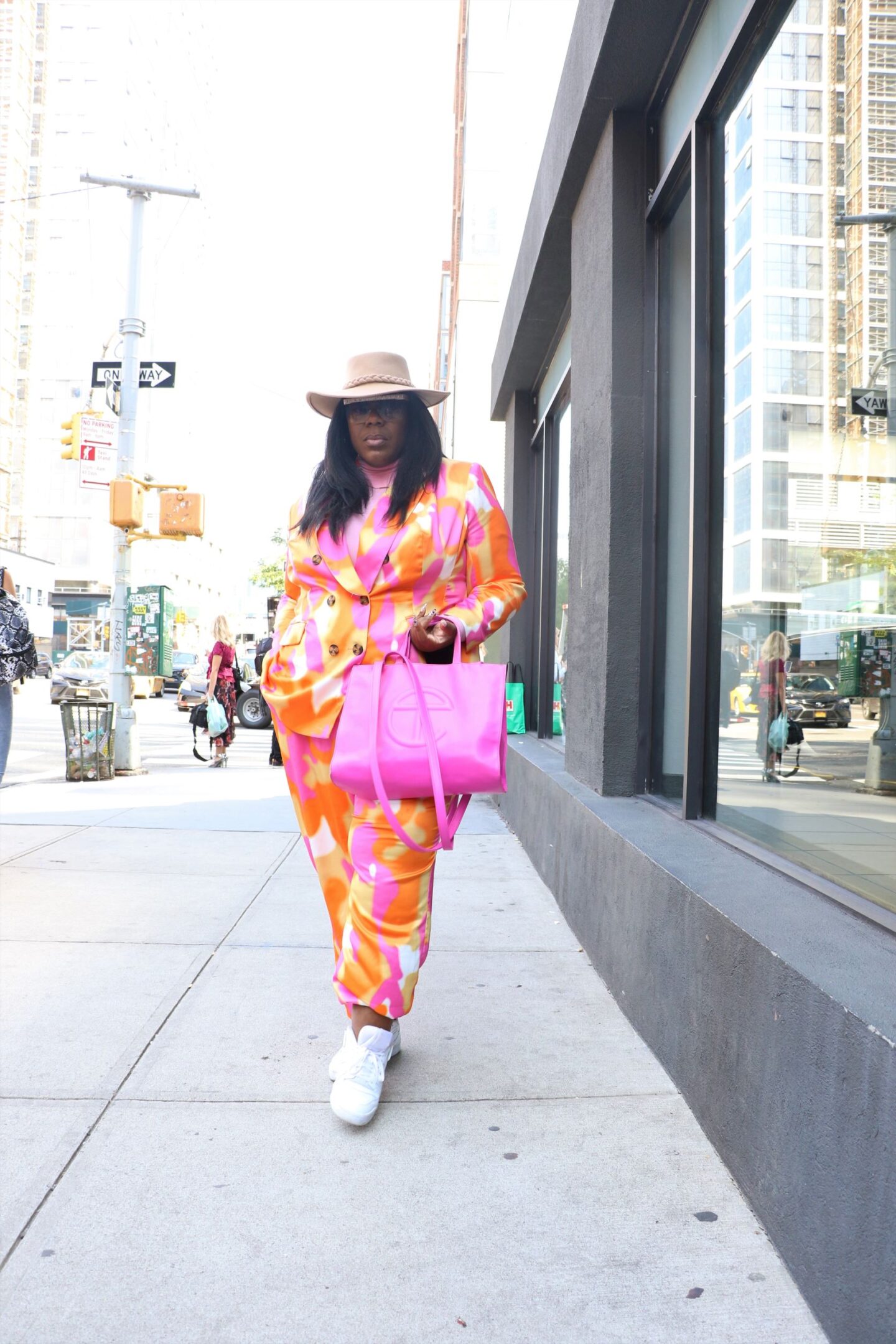 influencer wears a colorful pink and orange suit and pink telfar bag as a plus size street style outfit to new york fashion week